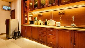 A kitchen with wooden cabinets, a refrigerator, a sink, and various appliances. - Villa Grand Mellow (Nuwara Eliya)