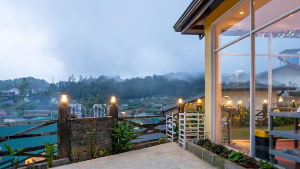 A terrace with a stone wall, a wooden fence, and a glass door leading to a dining area. - Villa Grand Mellow (Nuwara Eliya)
