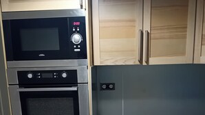 Una cocina con microondas, horno y armarios de madera.