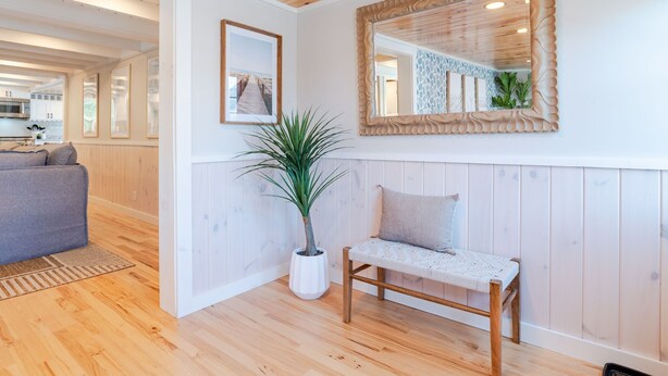 A modern living room with a wooden ceiling, a bench, a potted plant, and a framed picture on the wall.