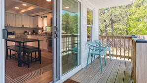 A covered outdoor area with a sliding glass door leading to a kitchen.