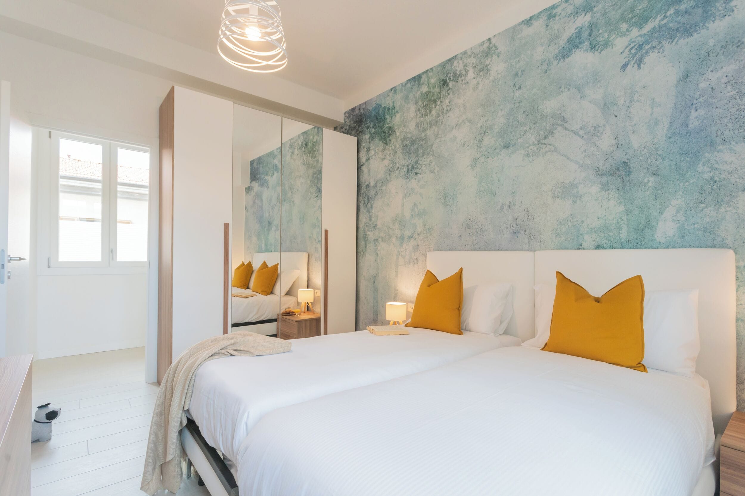 A modern bedroom with a large bed, a mirror, and a textured wall.