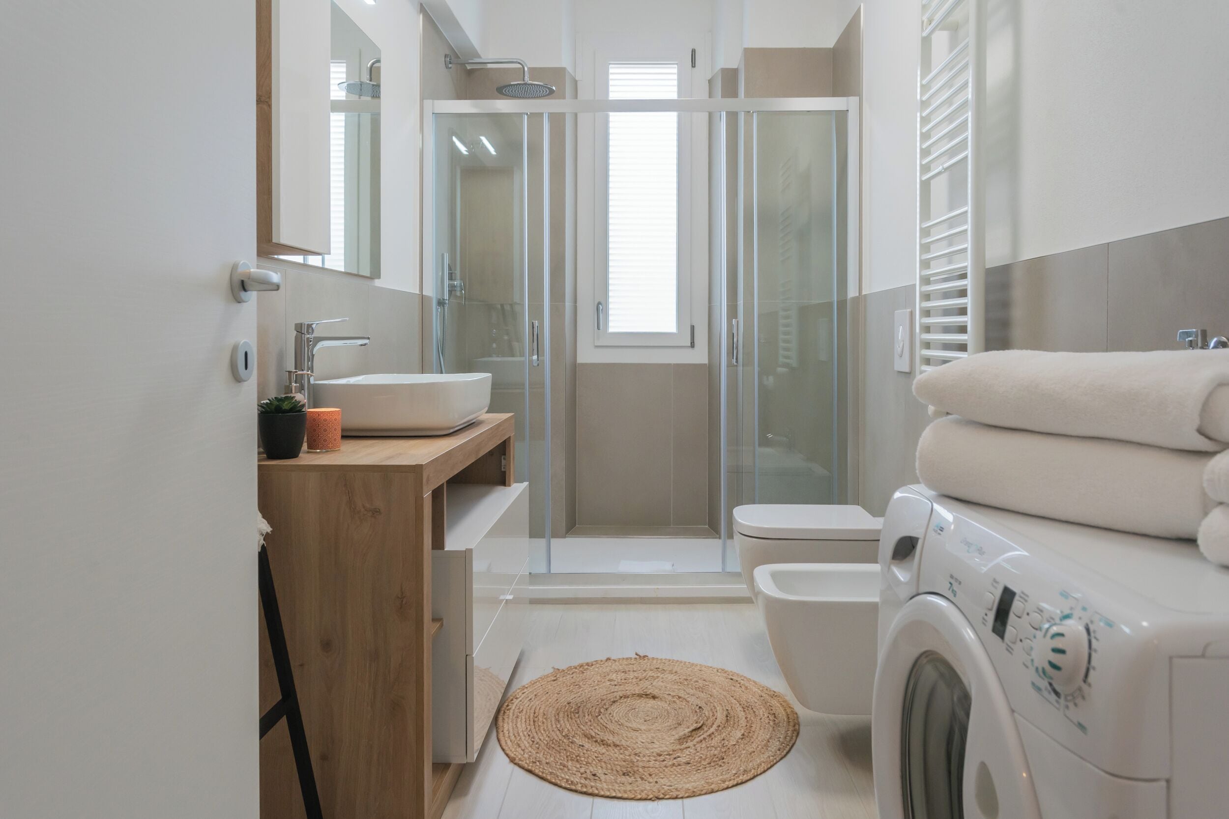 Un bagno moderno con box doccia in vetro, lavandino, WC e lavatrice.