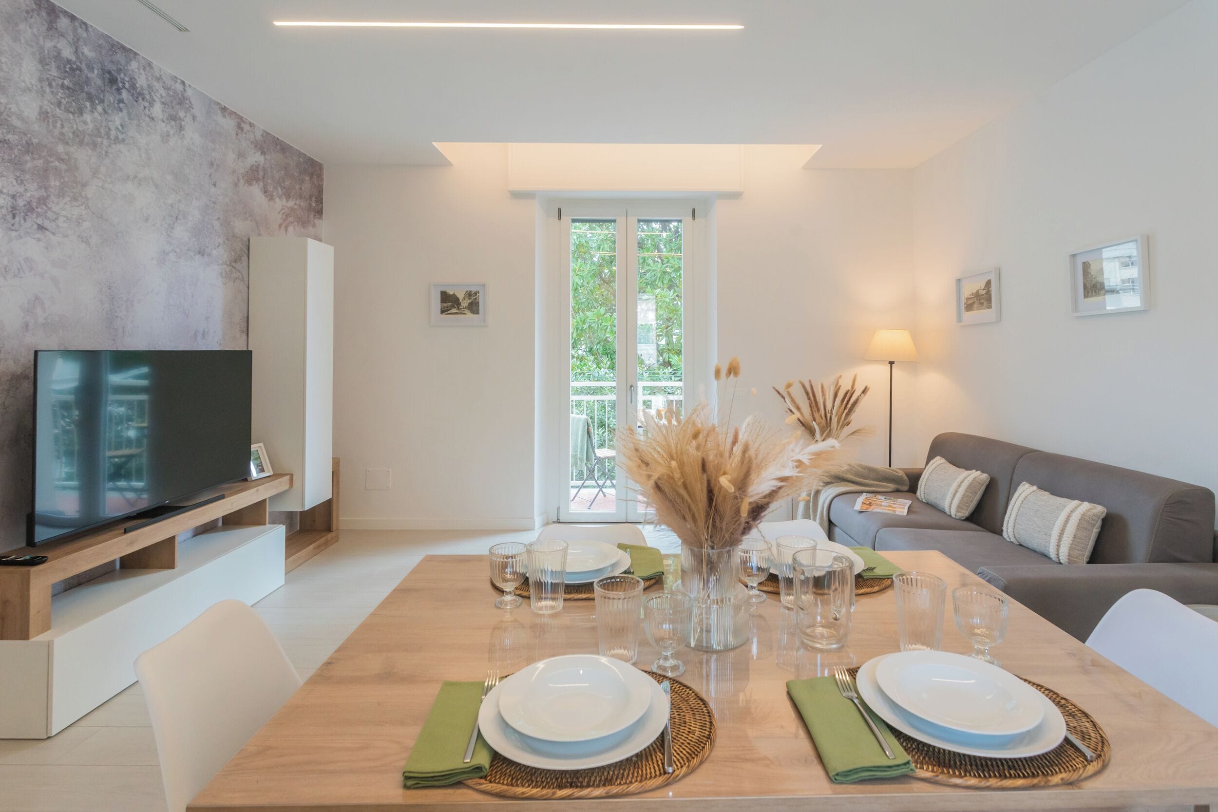 A modern living room with a dining area, a television, and a sofa.