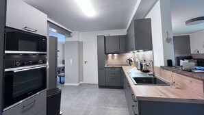A modern kitchen with built-in appliances, grey cabinetry, and a wooden countertop. - Shed 30 near Hamburg between the seas. Billiards, darts, sauna, very luxurious (Schmalfeld)