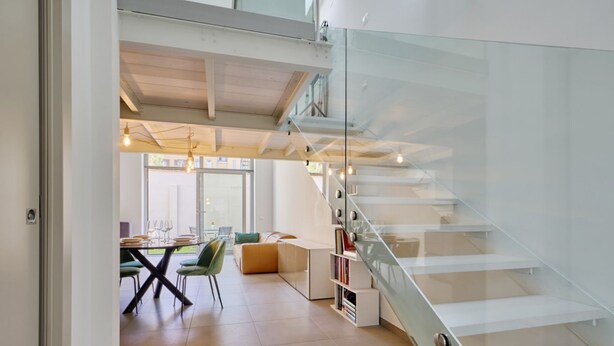 Een modern interieur met een trap, een eethoek en boekenkasten.