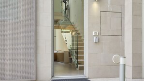 Een modern gebouw met een glazen deur, een metalen trap en een klein buitengebied met een abri.