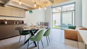 Een moderne keuken met een eethoek, grote ramen en uitzicht op buiten.