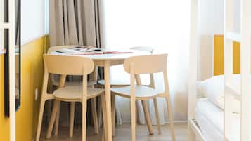 Une pièce avec un lit, une table et des chaises, et une fenêtre avec des rideaux.