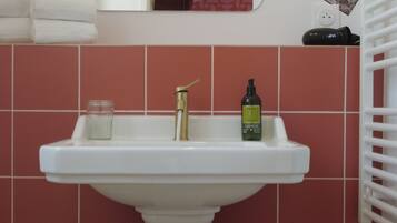 A bathroom sink with a gold faucet, a glass jar, and a bottle of lotion.