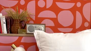 A neatly arranged bedside table with a white pillow, a radio, books, and a vase with dried plants.