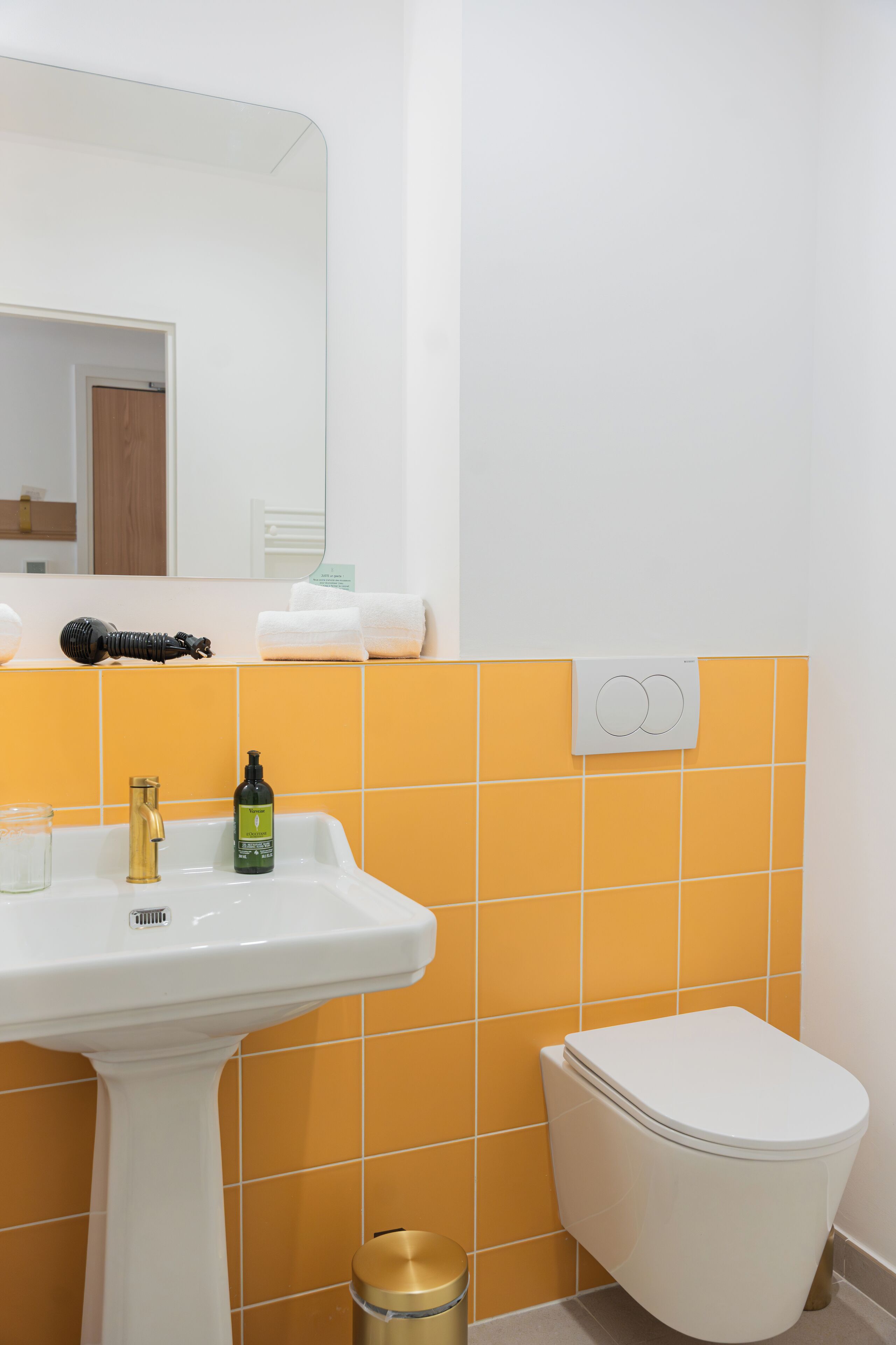 Een badkamer met een witte wastafel, een gouden kraan en een wit toilet.