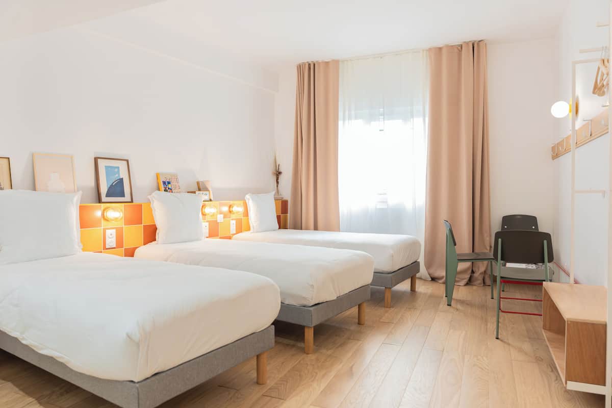 Ein Hotelzimmer mit zwei Betten, einem Schreibtisch und einem Stuhl.
