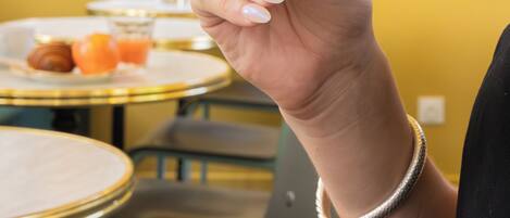 A hand holding a white cup, with a yellow wall and windows in the background.