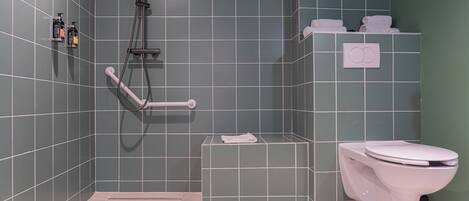 A bathroom with a shower, toilet, and a small shelf with towels.