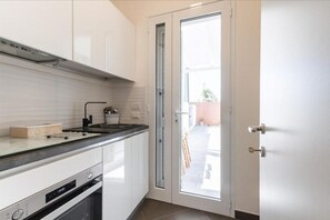 A kitchen with white cabinets, a black countertop, and a glass door leading outside.