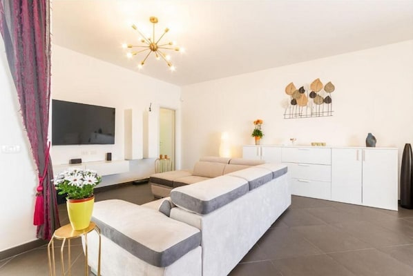 Una sala de estar moderna con sofá, televisión, comedor y cocina.