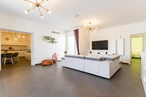 Una sala de estar moderna con sofá, televisor y comedor con sillas y una mesa.