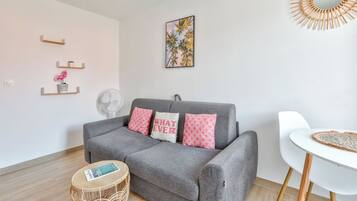 A modern living room with a grey sofa, white chair, and a small round table.