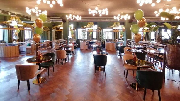 Un'ampia sala ristorante con soffitti alti, moderni lampadari e diverse disposizioni di posti a sedere, tra cui tavoli rotondi e sedie imbottite.