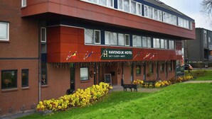 Un hotel con facciata rossa, numerose finestre e un cartello che indica la presenza di ristorante, camere e sale riunioni.