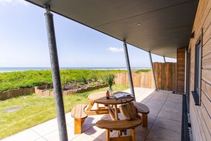 Une terrasse extérieure avec une table et des bancs, donnant sur une plage.