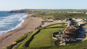 A coastal residential area with houses, a beach, and a cliff. - The Lighthouse is an end of terrace four bedroomed seafront retreat with a hot tub and incredible vi (Widemouth Bay)
