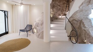 Un interior moderno con una escalera, una silla y un llamativo revestimiento de pared que simula roca.