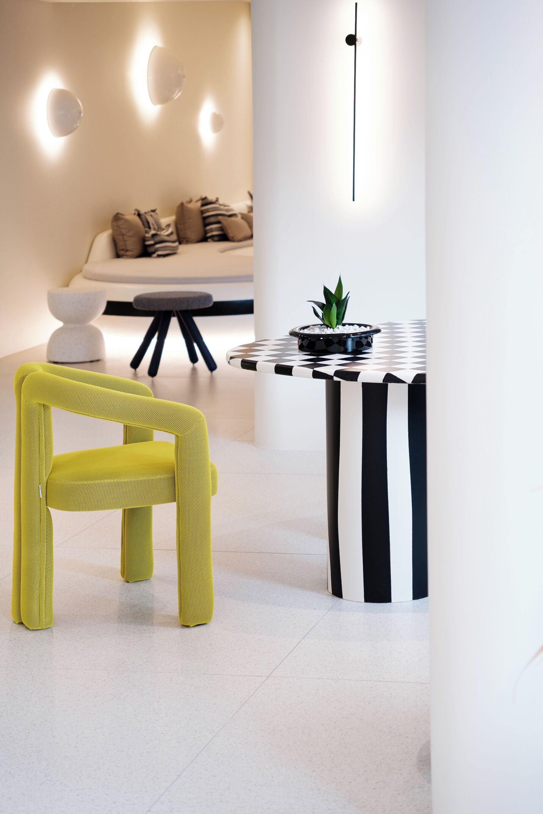 A modern interior with a yellow chair, a black and white checkered table, and a potted plant.