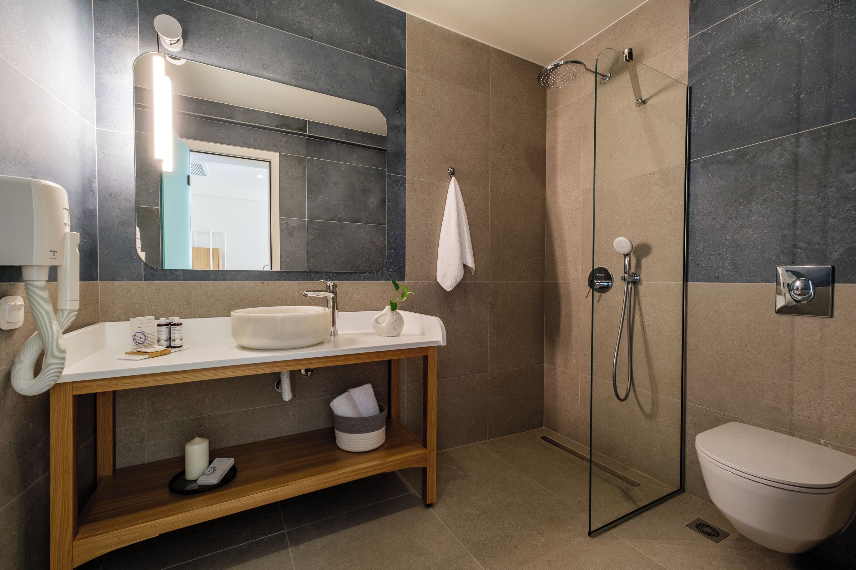 A modern bathroom with a glass shower enclosure, a white sink, and a wooden vanity.