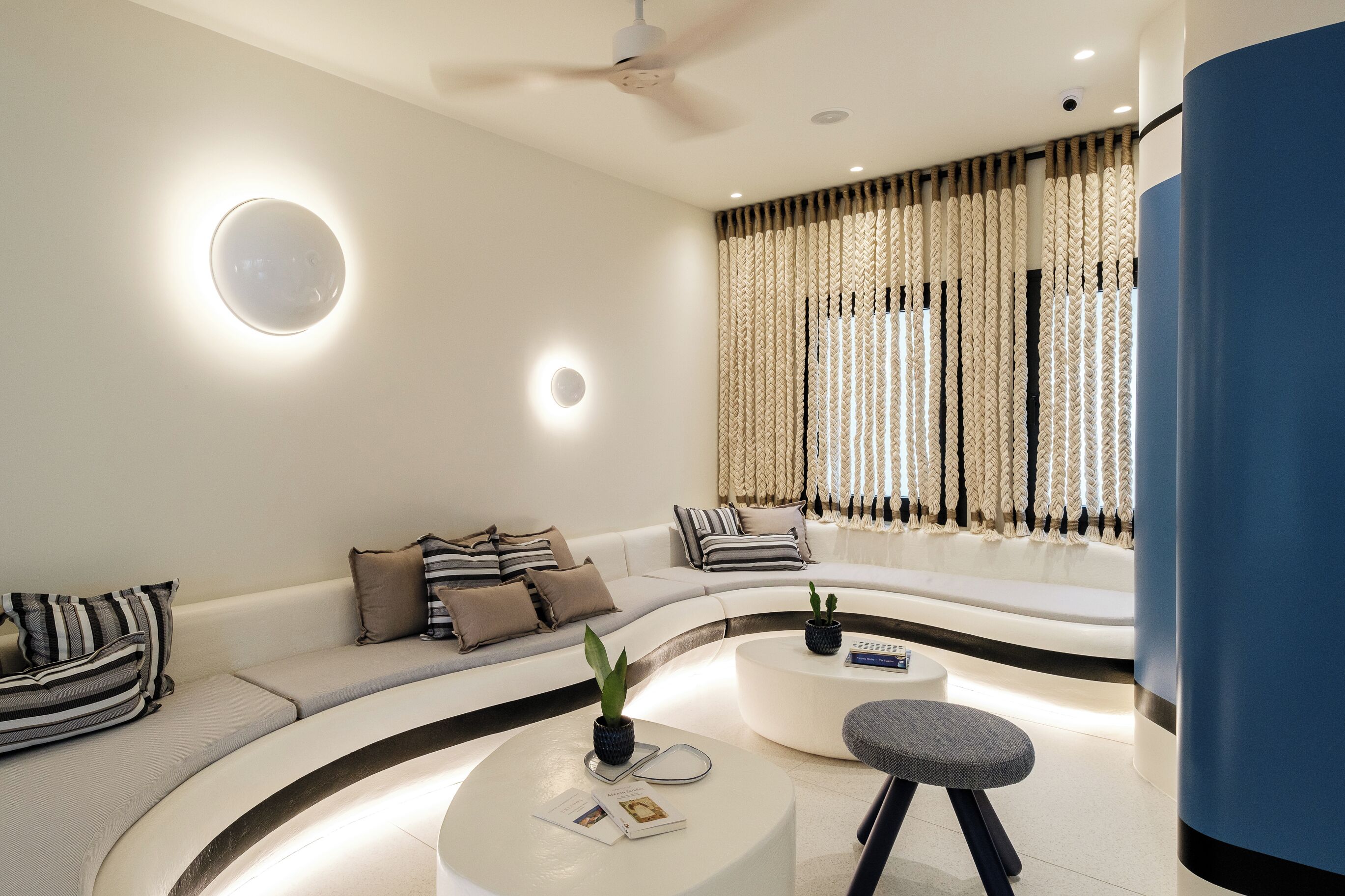 Un salon moderne avec un canapé incurvé, une table basse ronde et un ventilateur de plafond.