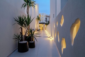 Un corridoio stretto con piante in vaso, un'area relax e un edificio dalle caratteristiche architettoniche uniche.