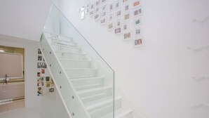 A modern staircase with glass railings and a wall decorated with framed photos. - HUGE 5 floors townhouse in central London NW6 (London)