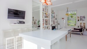 A modern, bright living room with a white dining area, a flat-screen TV, and a wall adorned with photos. - HUGE 5 floors townhouse in central London NW6 (London)
