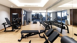 A modern gym with various exercise equipment, large windows, and a bright interior. - LUX Studio Near B.khalifa (Dubai)