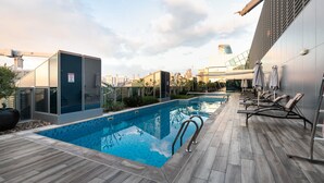 A rooftop pool with a modern design, including a glass enclosure and lounge chairs. - LUX 1BR Near B.khalifa (Dubai)