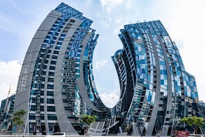 A modern building with a unique curved design, featuring multiple glass windows and a reflective facade. - LUX Studio Near Burj w Canal Views (Dubai)