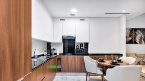 Una cocina moderna con una isla central, muebles blancos y un comedor con mesa y sillas redondas.