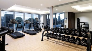 A modern gym with treadmills, a rowing machine, and a rack of dumbbells. - Premium Corner Apt 1BD in Jone w Canal View (Dubai)