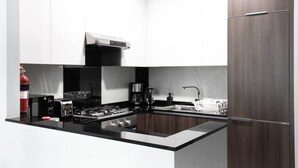 A modern kitchen with a central island, stainless steel appliances, and a dark wood cabinet. - Premium Corner Apt 1BD in Jone w Canal View (Dubai)