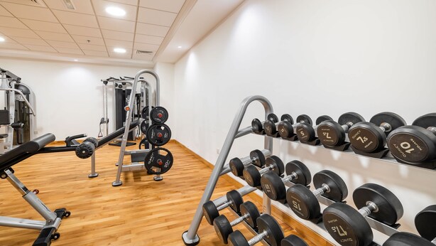 A gym with weightlifting equipment, including dumbbells and a bench press. - Pool View 1BR on Palm Jumeirah (Dubai)