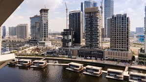 A modern cityscape with high-rise buildings, a marina with boats, and a prominent 'BINGHATTI' sign. - LUX Waterfront 1BR Near B.khalifa (Dubai)