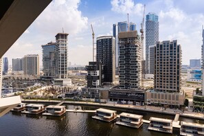 Un paysage urbain moderne avec de hauts immeubles, une marina remplie de bateaux et un panneau bien visible portant l’inscription « BINGHATTI ».