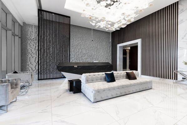 Un hall d’entrée moderne avec un canapé blanc, un élément décoratif noir et un luminaire au plafond original.