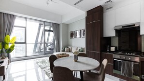 A modern kitchen with a dining area, large windows, and a view of the city. - LUX Waterfront 1BR Near B.khalifa (Dubai)