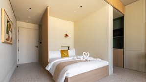 Een moderne slaapkamer met een groot bed, een houten hoofdbord, een klein nachtkastje en een garderobe.