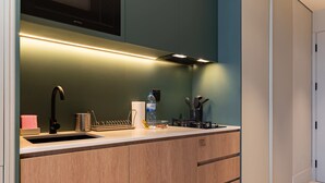 A modern kitchen with a built-in sink, wooden cabinets, and a stainless steel faucet. - Deluxe Studio With Balcony Full Burj Khalifa View (Dubai)