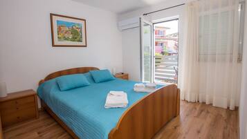 Un dormitorio con una cama de madera, una mesita de noche, una ventana con cortinas y un cuadro enmarcado en la pared.