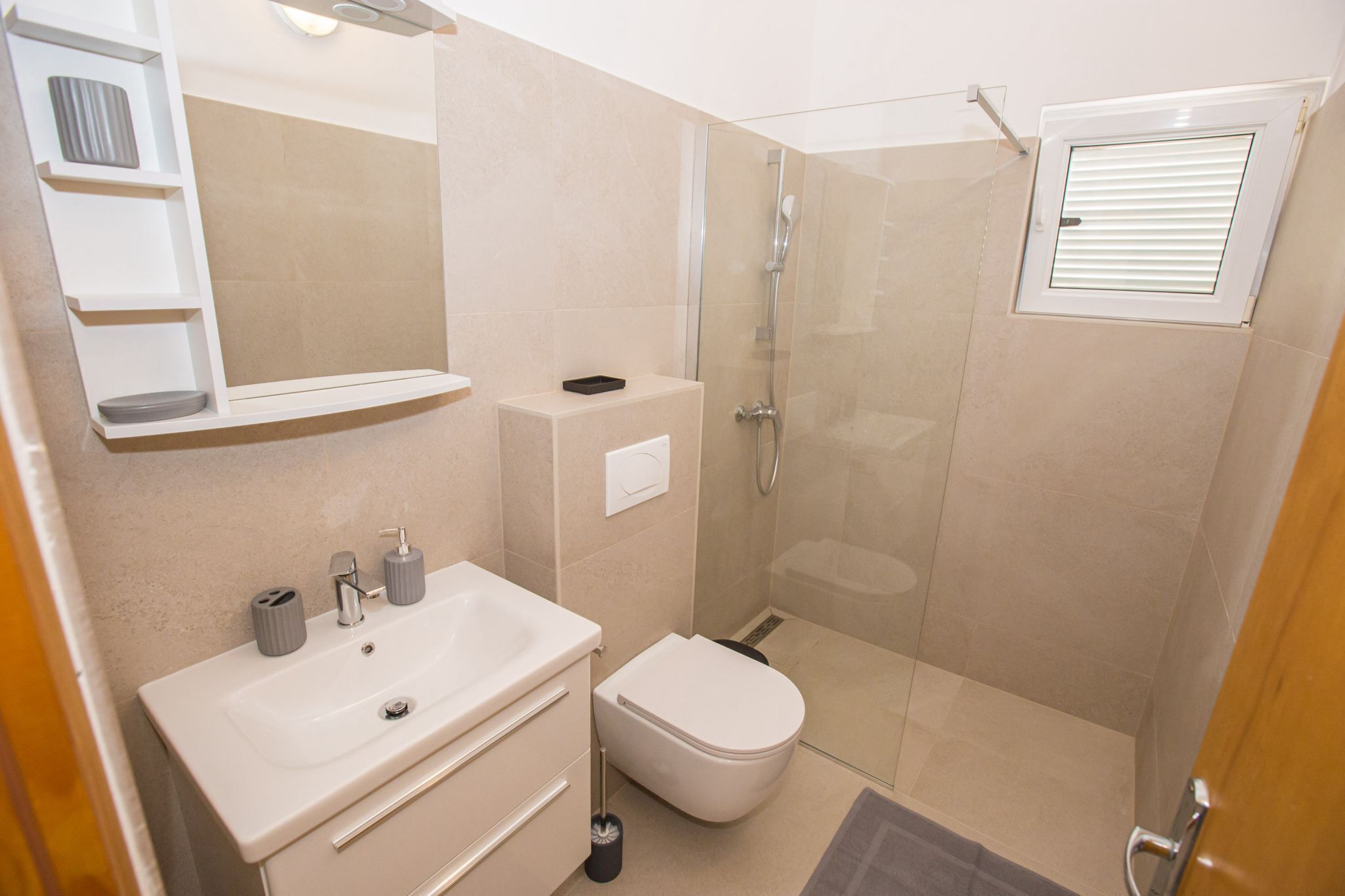 A modern bathroom with a sink, toilet, and glass-enclosed shower.