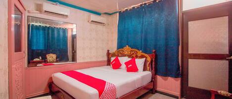 A bedroom with a wooden bed, a mirror, an air conditioner, and a window with curtains.